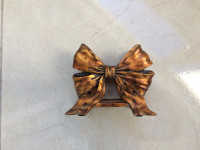 Starinski stalak za salvete, izgleda poput mašne, bakreno-zlatne boje