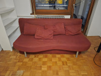 Crveni kauč na razvlačenje sa spremnikom i jastucima