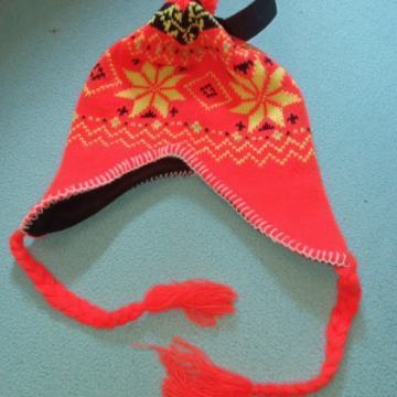 Kapa za zimu narančaste boje sa pokrivalima za uši i pletenicama